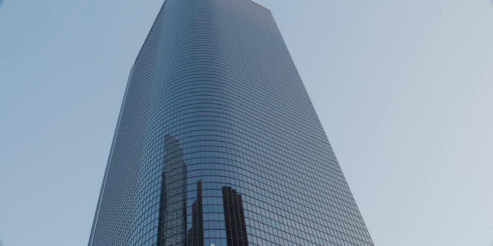 The mirror finish on the windows of a tall skyscraper reflect the sky and other buildings