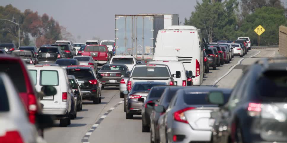 Heavy traffic on freeway with trees at a distance