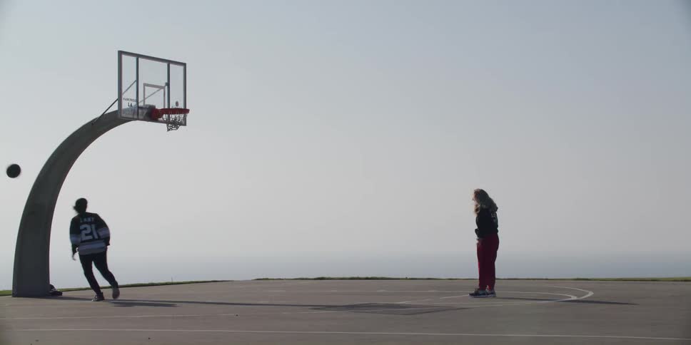 Two people are playing basketball outdoors