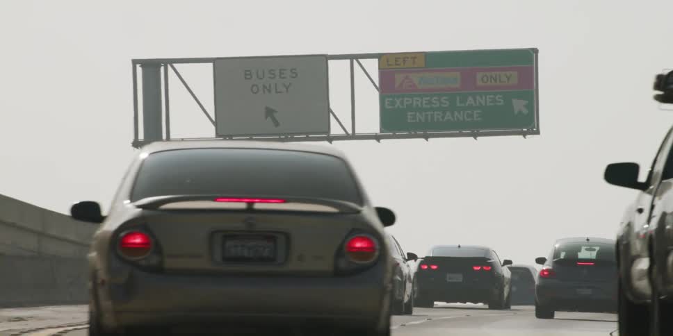 Traffic on a highway goes uphill and moves into the express lane