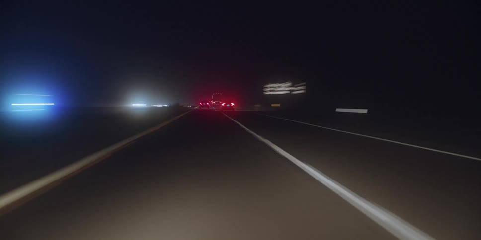 Cars are driving on a highway at night