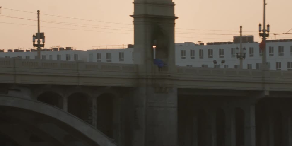 A view across town of the sun rising above a building and a close up view of a bridge