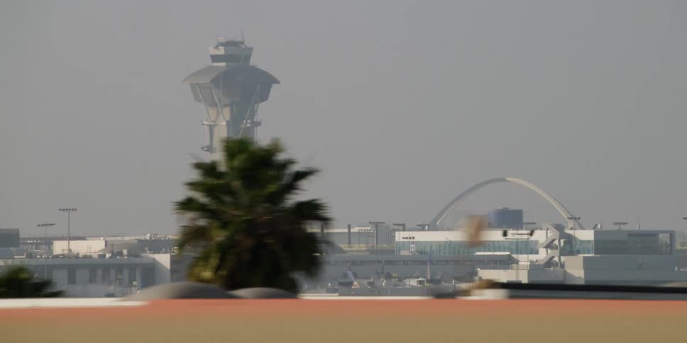 A large tower building protrudes above the city buildings seen from a freeway