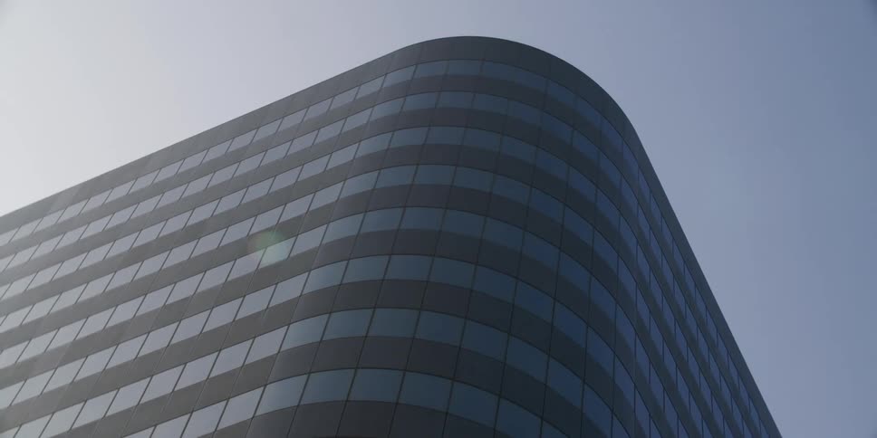 A tall office building is shown in a downtown city