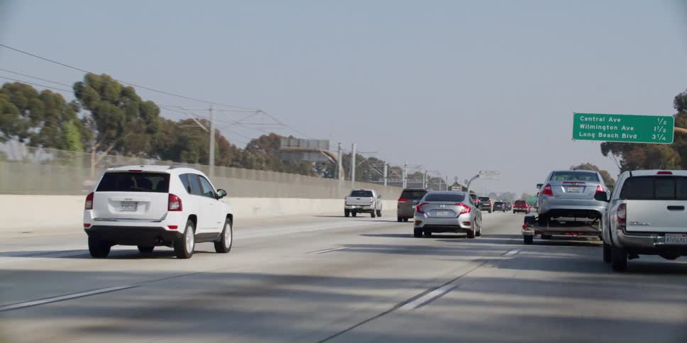 The sun shines on cars and trucks traveling on a highway