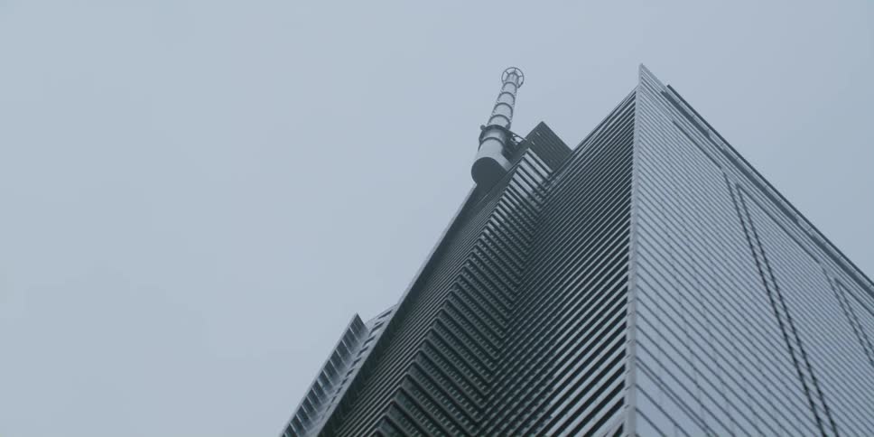 A spiral steeple sticks up from the side of a tall skyscraper