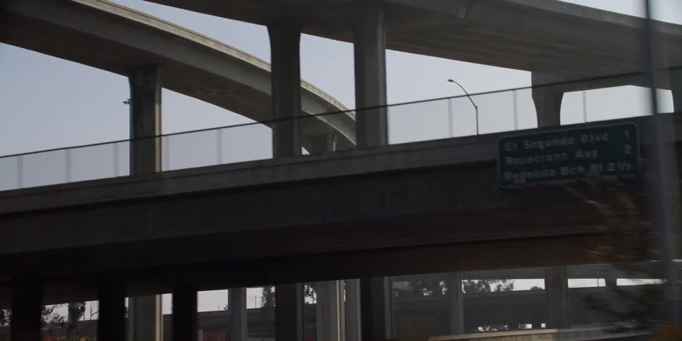 Automobiles travel on a freeway and go under bridges along the way and other vehicles are on the bridges