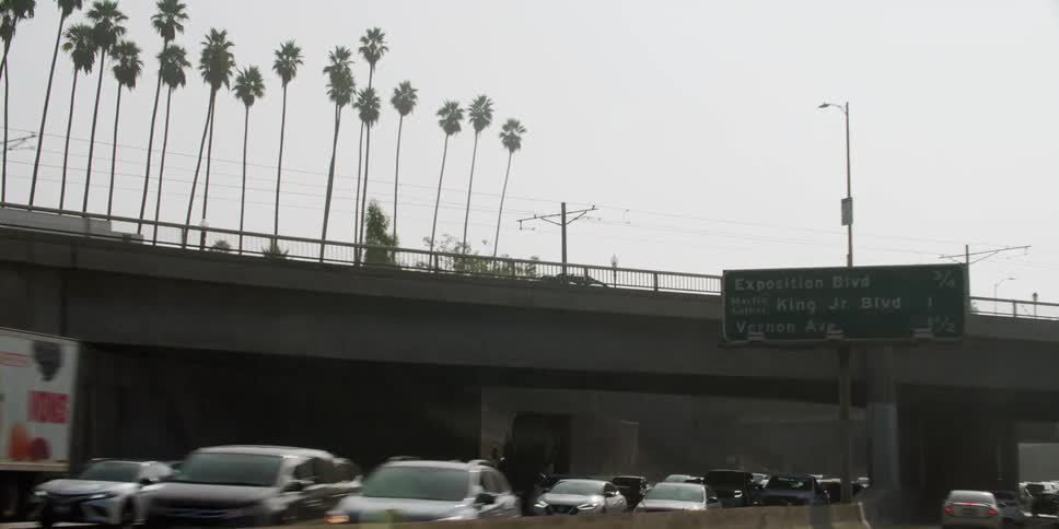 Automobiles are traveling on a busy highway and through an overpass