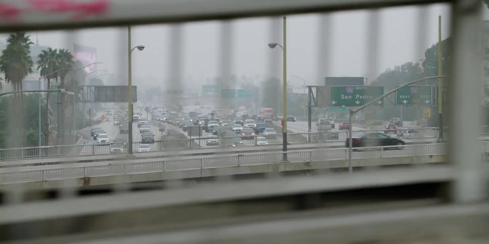 Cars cross bridge over bushy controlled access freeway on foggy day