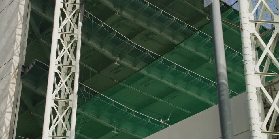 A man plays golf from an upper level of a multi level driving range