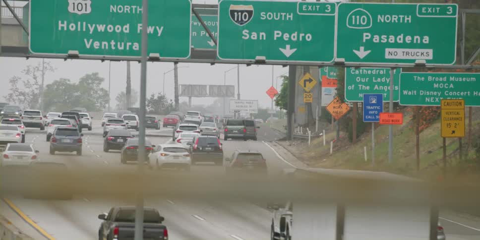 Traffic on a busy highway moves under road signs and goes slowly