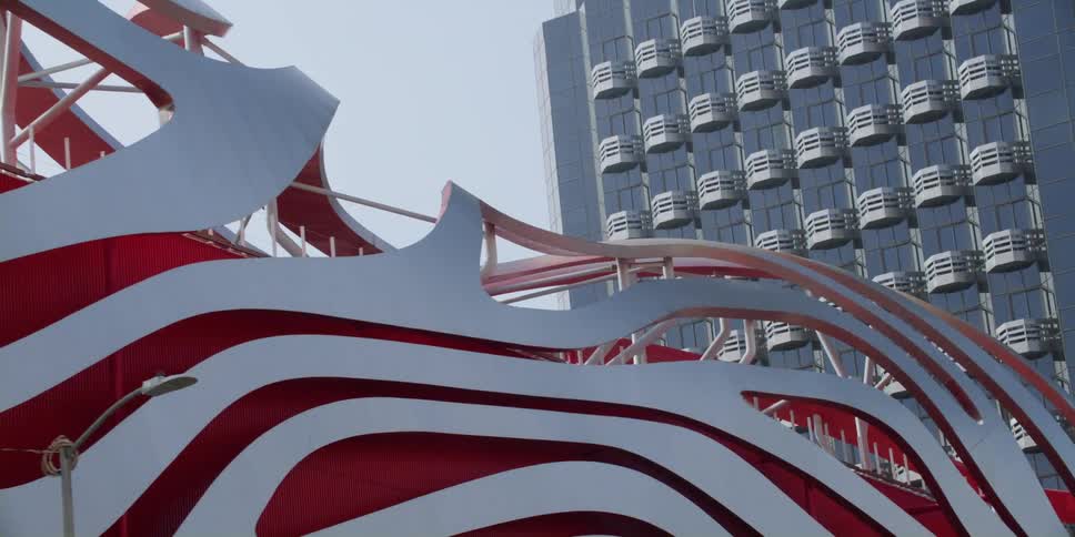 A uniquely designed building sits in front of a large glass building