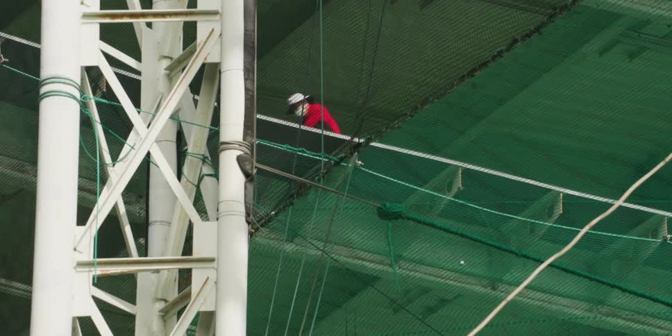 A man is standing on a balcony and golfing