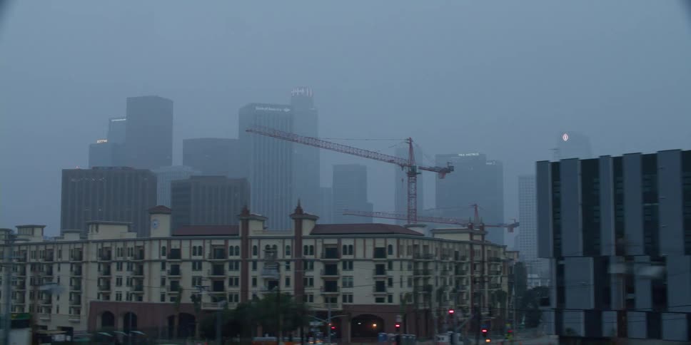 View of a big city covered in fog with big skyscrapers at a distance and smaller buildings in the front