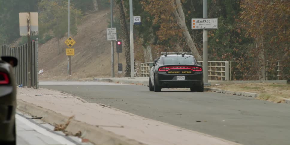 A vehicle drives past a police car parked near a ramp