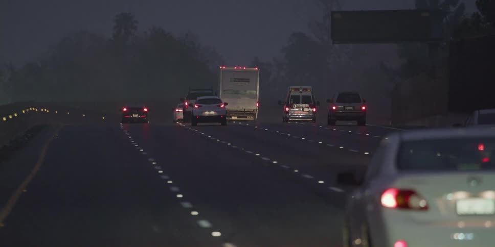 Vehicles drive down a multi lane highway in heavy traffic at night