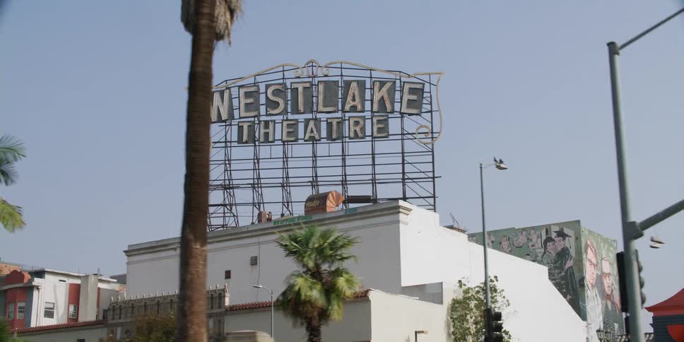 Vehicle drive past a theater in a city