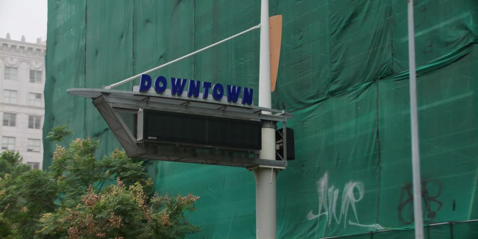 A large green tarp covers a downtown building under construction