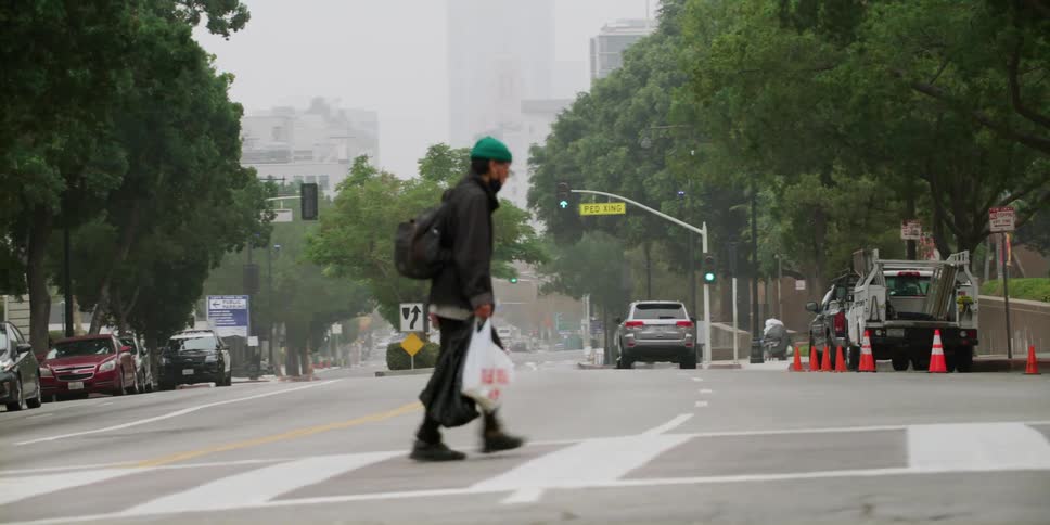 Pedestrian carrying shopping bags walking across crosswalk in the city