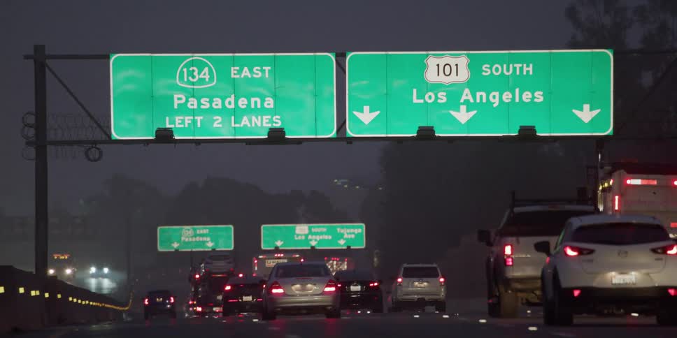 Heavy traffic flows to and from along divided controlled access highway at night