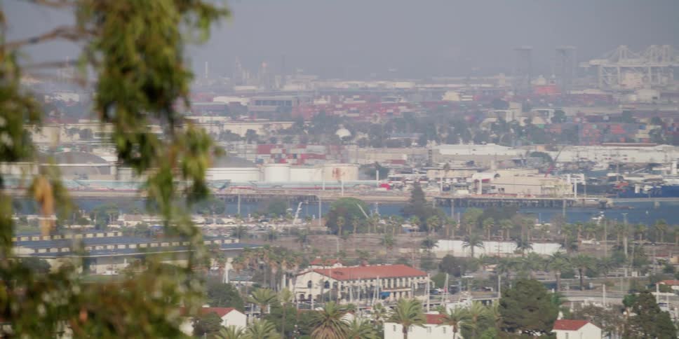 An elevated view of a town with large shipping ports and a canal on a hazy day