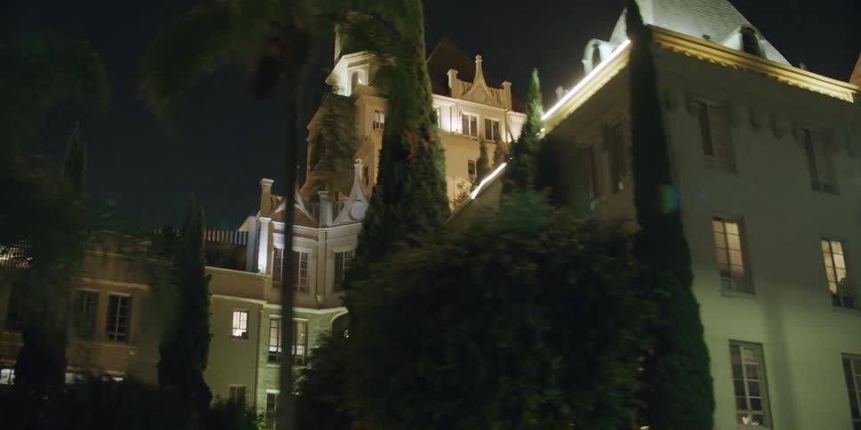The hollywood tower stands near the street and a bridge crossing at night