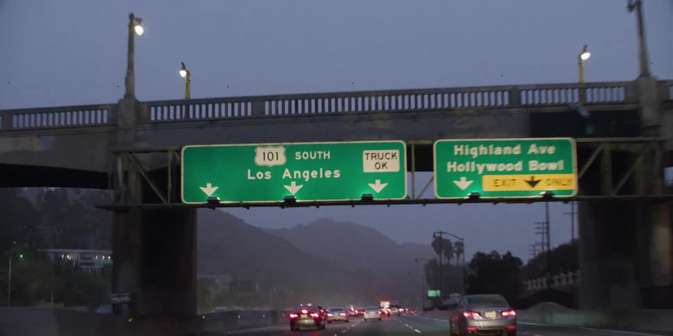 Automobiles are traveling on a highway and through an overpass