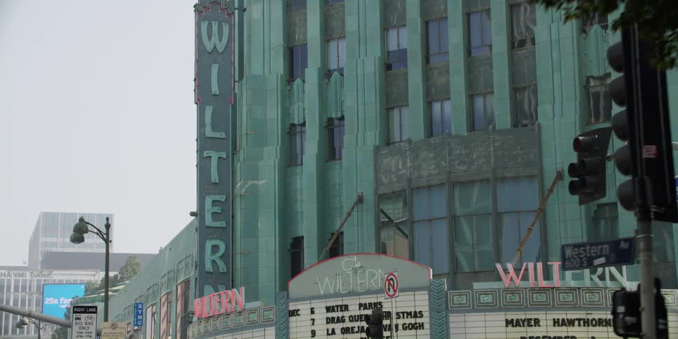 A theater building sits with a marquee advertising the upcoming events