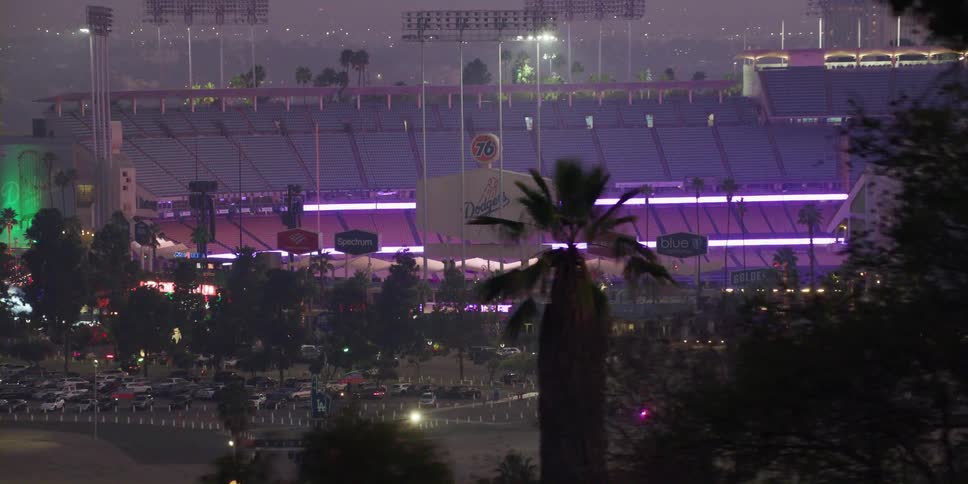 Cars are parking at a stadium at night