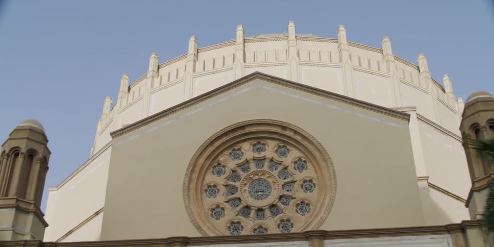 A round ornate window sits on the front facade of a domed building