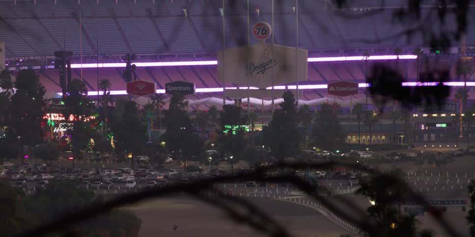 Cars are parked outside of a sports stadium at night