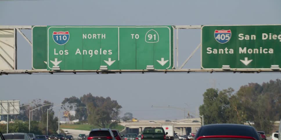 Traffic moves on a highway and a sign above the road is north los angeles