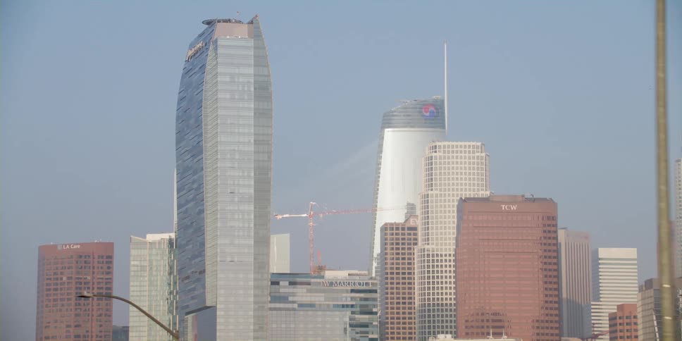 Tall skyscrapers are seen in a clear sky as traffic moves on the street