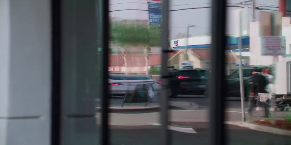 Pedestrians and cars can be seen reflected in building glass