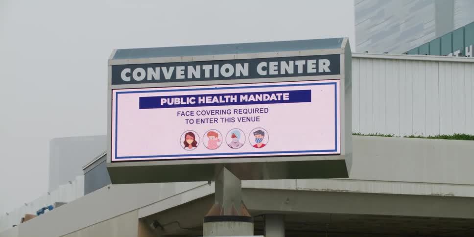 Passing by a video display at a convention center in the downtown area of a large city on an overcast and foggy day