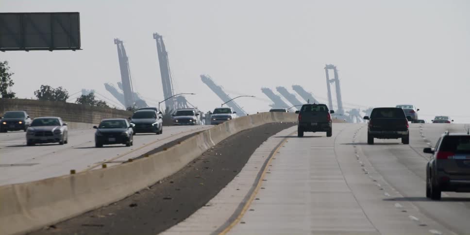 Vehicles drive on a multi lane highway past a construction site