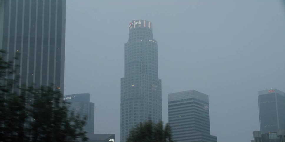 Exterior view of high rise office buildings in fog seen from moving car on highway
