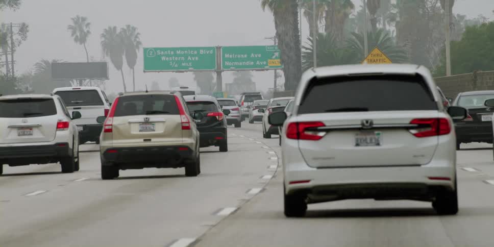 Automobiles are traveling on a busy highway and through an overpass