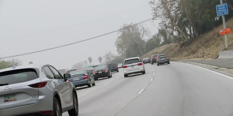 Automobiles are traveling on a highway and through an overpass
