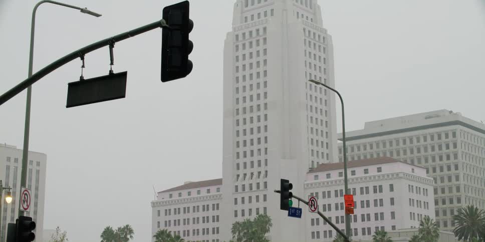 A truck drives past high rise buildings in a city