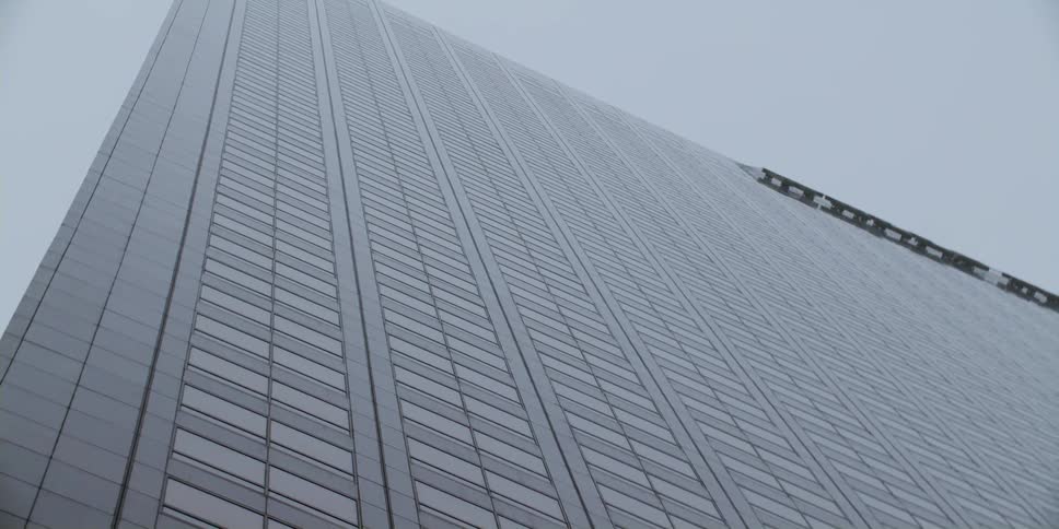 Looking up at a tall skyscraper in a hazy sky