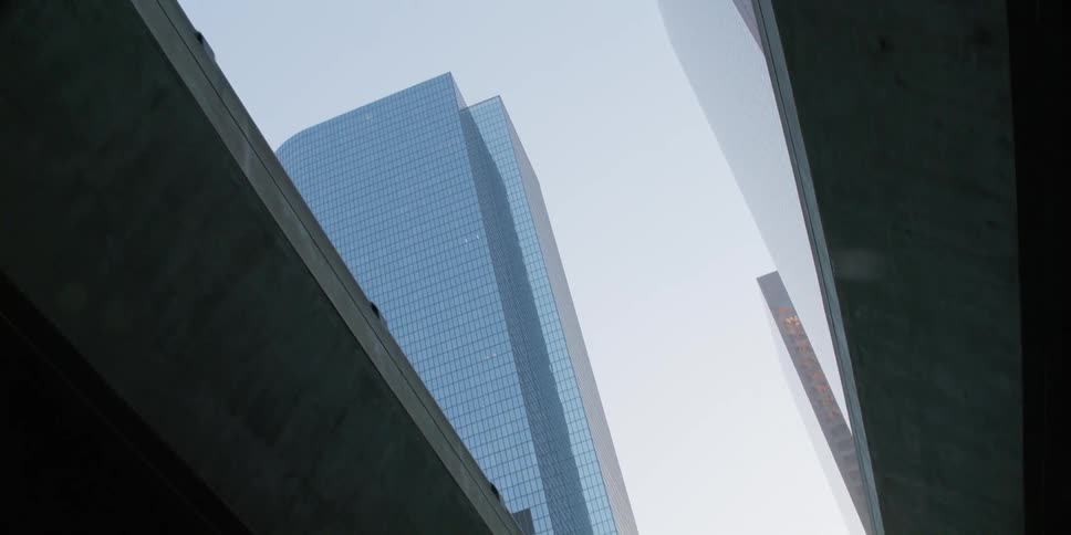 A road and businesses sit under a bridge running through downtown