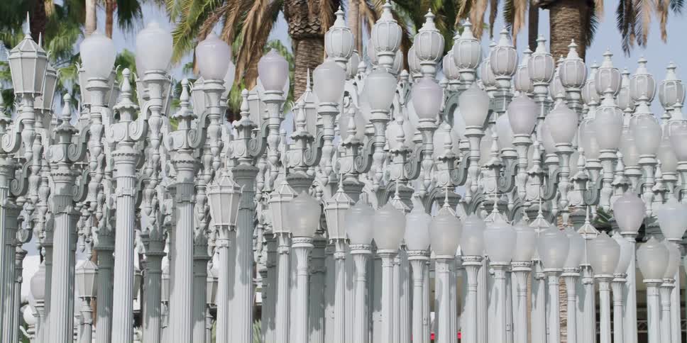 Pedestrians move around collected grouping of white street lamps