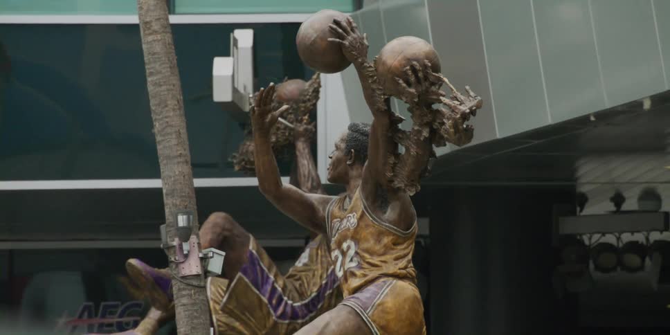 Two statues of basketball players are outside the building
