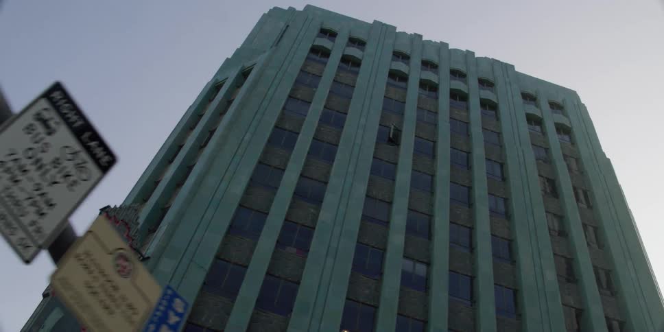 Empty tall building with multiple windows with traffic signs and light poles in front of it