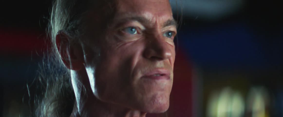 Middle aged and blue eyed man with gray ponytail works out in gym