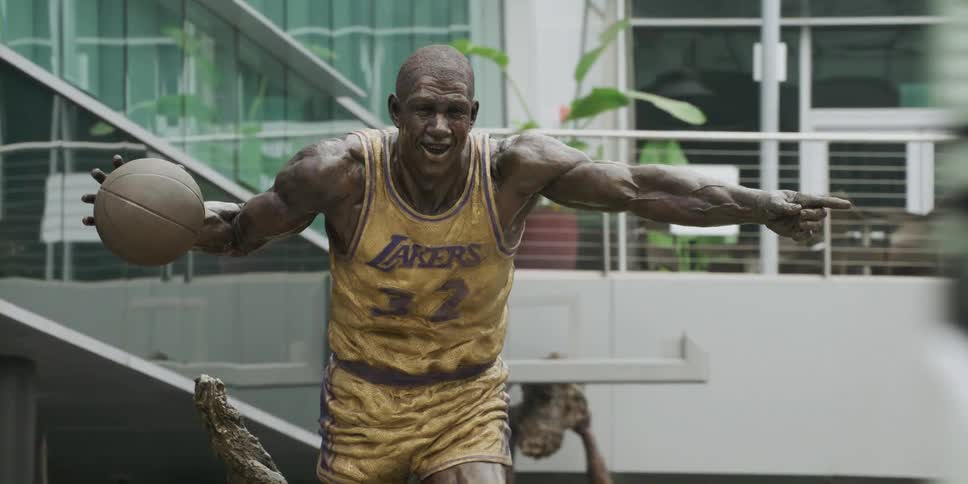 A statue of a basketball player is outside of a stadium