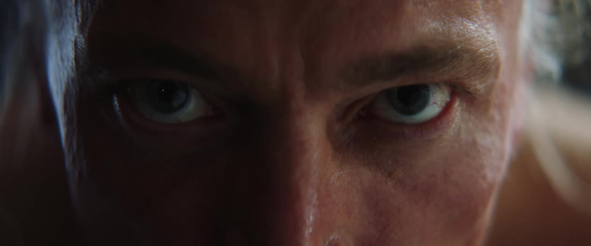 Midde aged and blue eyed man with gray hair stares at camera in the gym