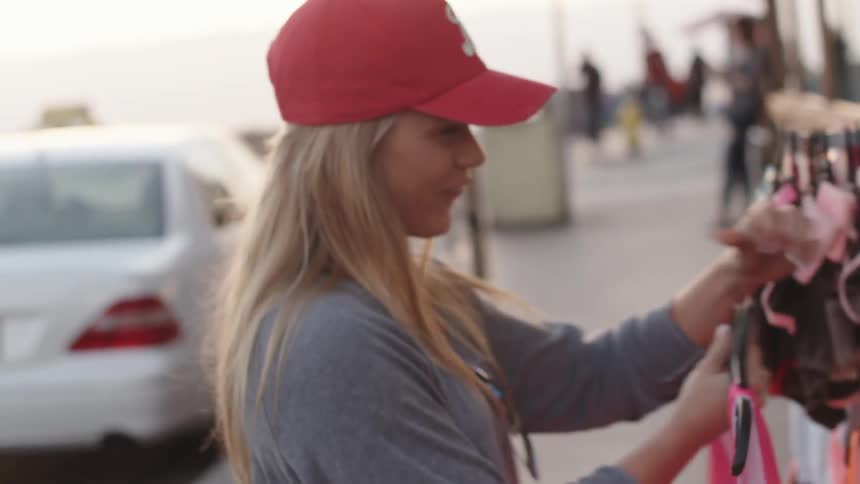 A woman in a red hat shows off a pink shirt