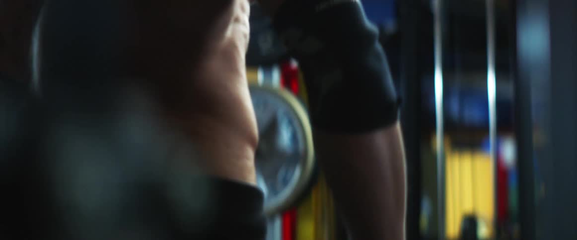 Muscular man with gray ponytail works out in gym